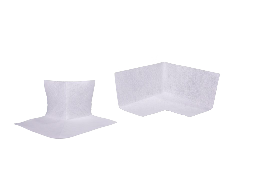 codex_Dummy_AX_700_Ecken_2024-04 Two white L-shaped corner protectors made of soft non-woven padding displayed against a white background. The pieces show a slightly textured surface and visible seam lines; the left one is shown from a slight angle revealing the inner corner and flat base flange, the larger right one shows the outer corner and top edge. They are studio-lit with minimal shadows and are intended as protective cushions for furniture edges or packaging.